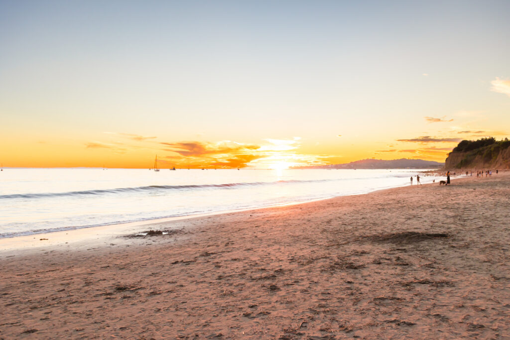 Victoria and Jonathan walking along Butterfly Beach during sunset engagement photos in Santa Barbara.
