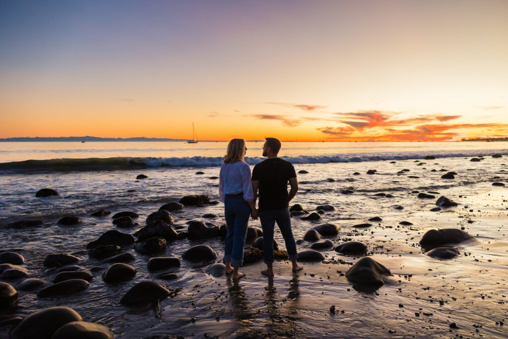 Victoria and Jonathan walking along Butterfly Beach during sunset engagement photos in Santa Barbara.