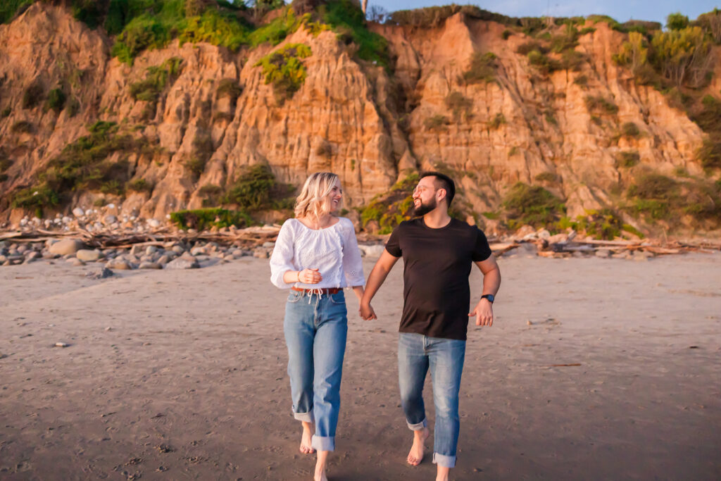 Victoria and Jonathan walking along Butterfly Beach during sunset engagement photos in Santa Barbara.
